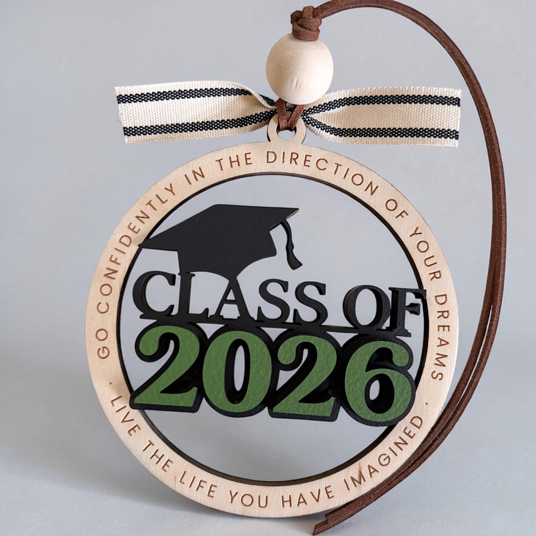 Decorative ornament with 'Class of 2026' text and graduation cap silhouette on a gray background.