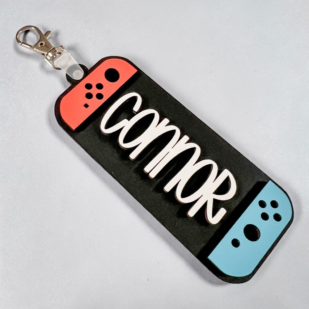 Keychain designed like a gaming controller with 'Connor' engraved on a gray background